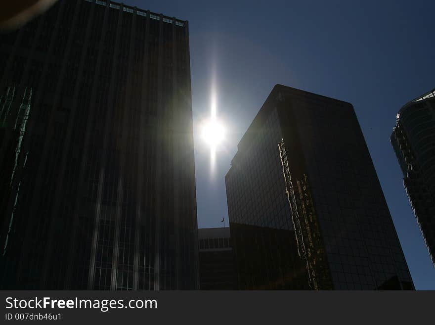 Silouette of downtown office towers with sun gleaming behind. Silouette of downtown office towers with sun gleaming behind.