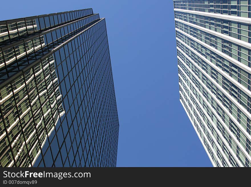 Looking up at two corporate downtown office buildings toward the blue sky. Perfect for corporate brochure. Looking up at two corporate downtown office buildings toward the blue sky. Perfect for corporate brochure.