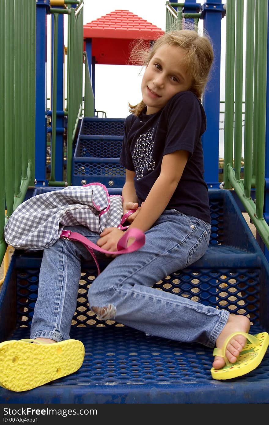 Young school girl sitting on playground equipment steps at recess. Young school girl sitting on playground equipment steps at recess