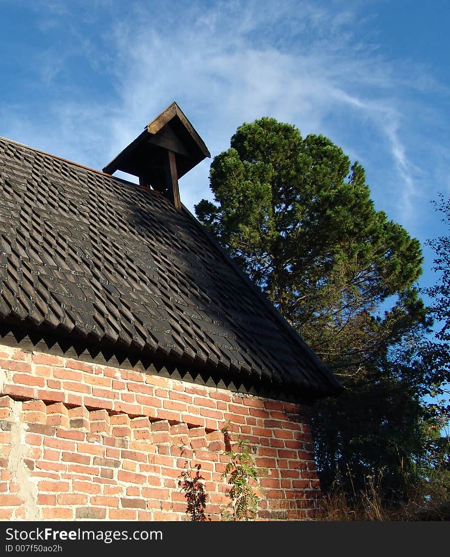 The nature without the Photoshop: wall of a chapel, pine and spiral cloud above it