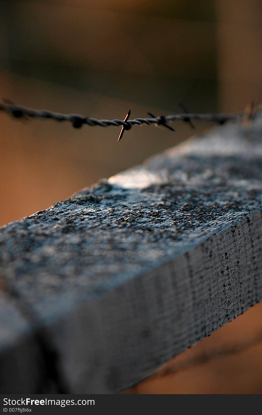 Closeup of barbed wire fence and old gray wooden railing