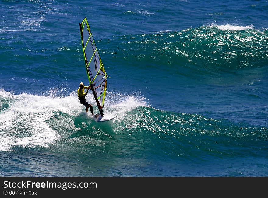 A windsurfer rides a wave while sailboarding in Hawaii. A windsurfer rides a wave while sailboarding in Hawaii