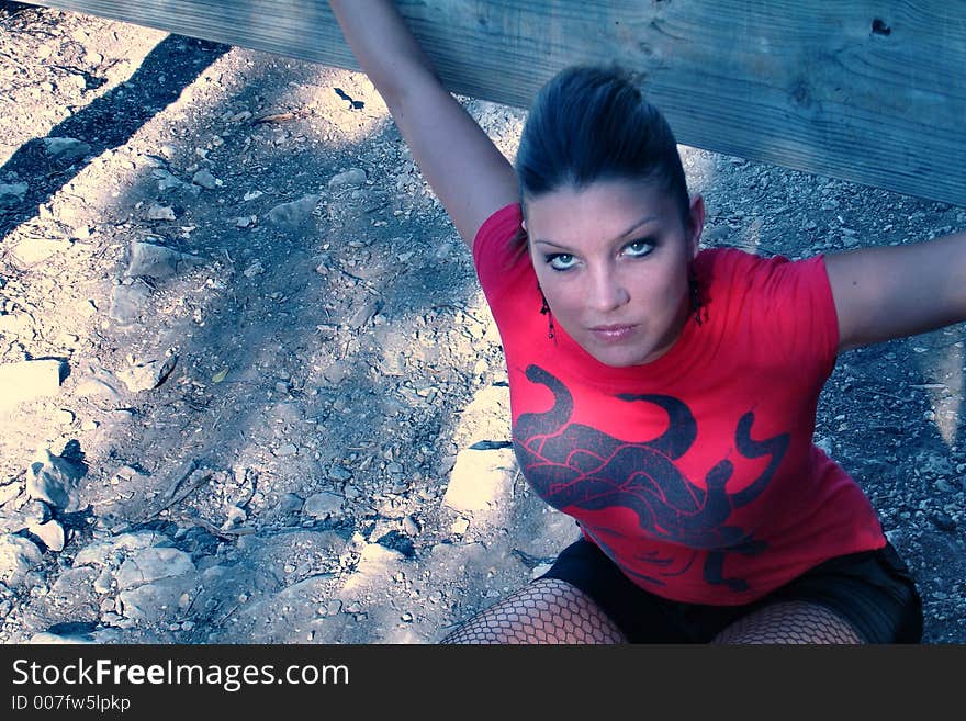 Woman posed kneeling by a rail in a park.. color. Woman posed kneeling by a rail in a park.. color.