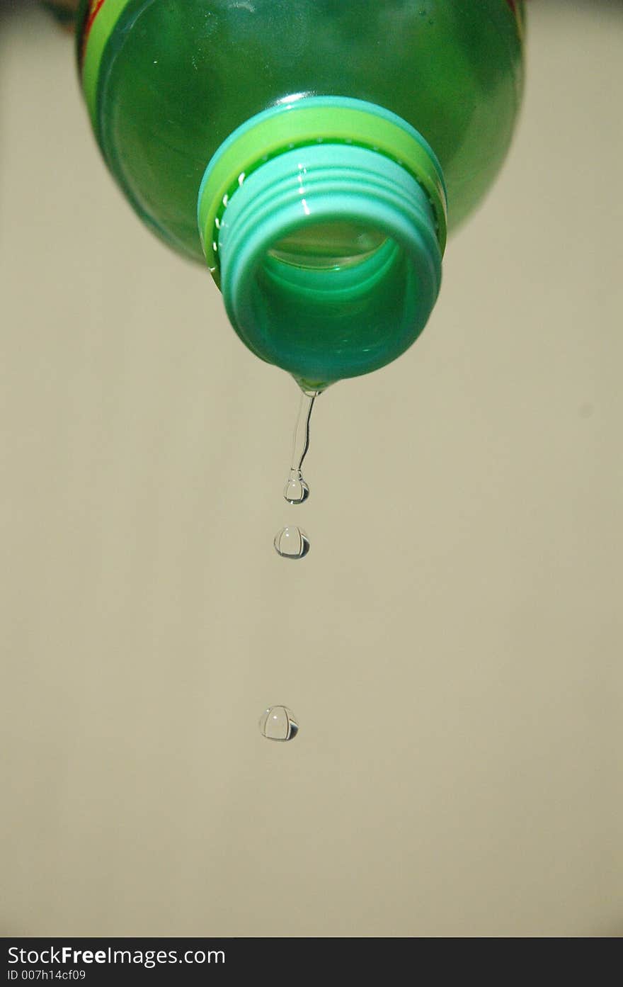 Water drips from a green bottle. Water drips from a green bottle.