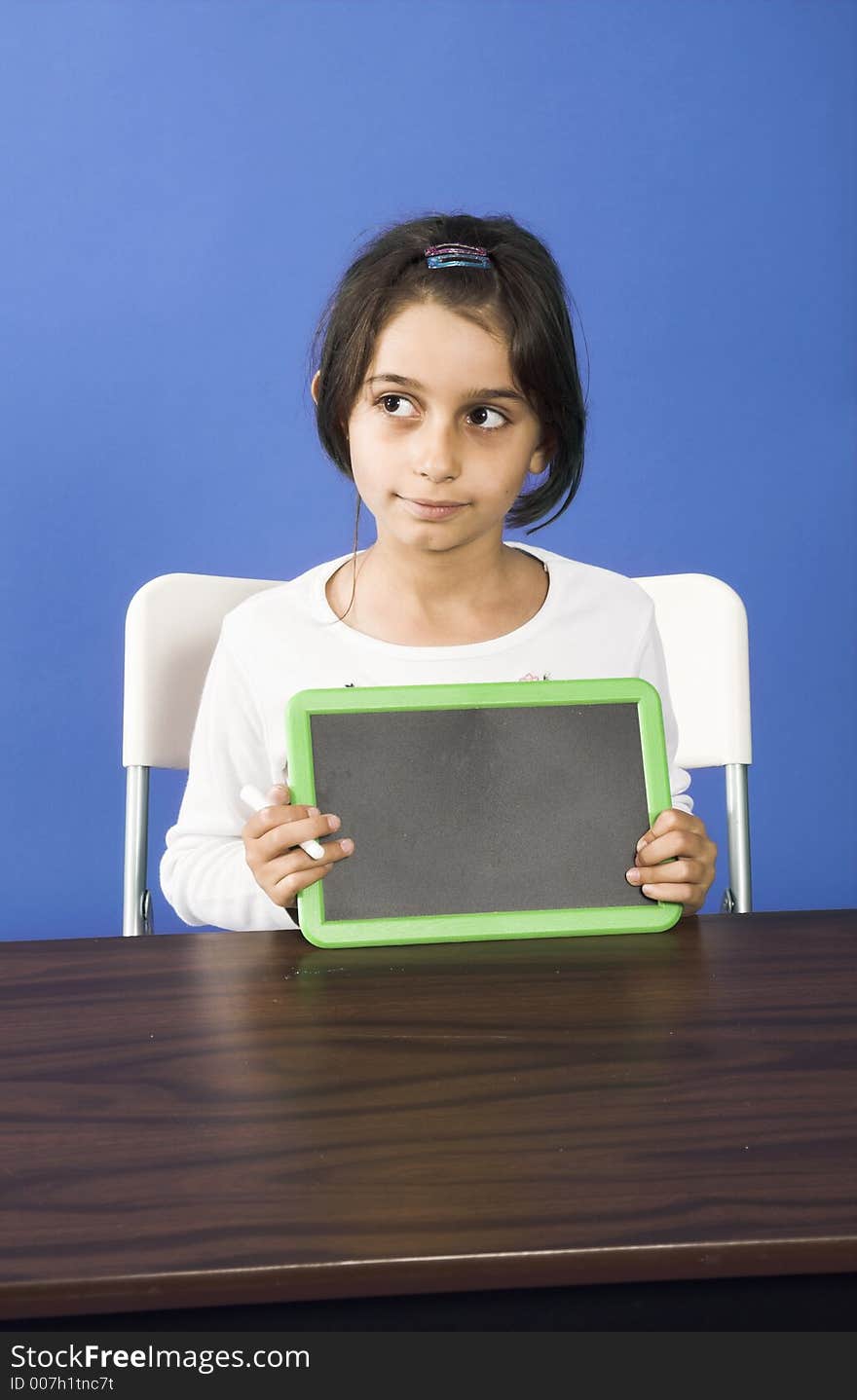 Little girl showing chalkboard in classroom