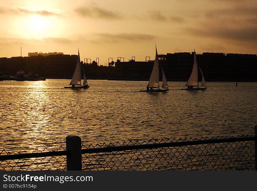 A sunset above an urban skyline with sailboats in the foreground. A sunset above an urban skyline with sailboats in the foreground