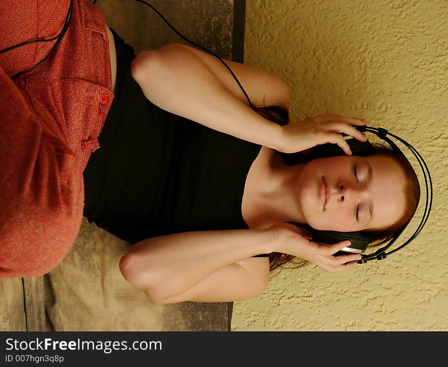 A teenager with headphones sitting on a sofa. A teenager with headphones sitting on a sofa.