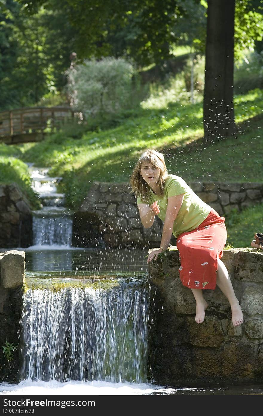 Blond lady is splashing water in the water fall. Blond lady is splashing water in the water fall.