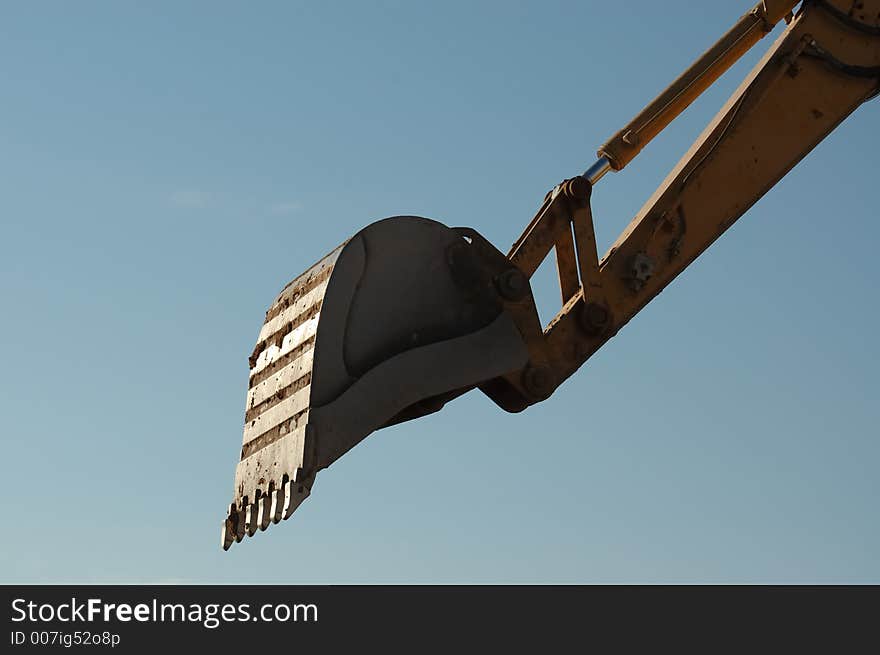 Close-up shot of trackhoe bucket at work against the blue sky morning. Close-up shot of trackhoe bucket at work against the blue sky morning.