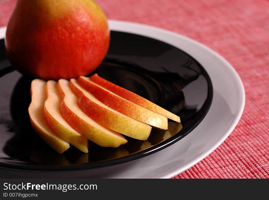 Forelle pear whole and sliced on black plate. Forelle pear whole and sliced on black plate