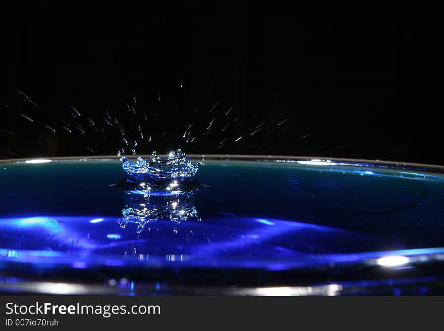 A blue water drop with a blurred splash. A blue water drop with a blurred splash