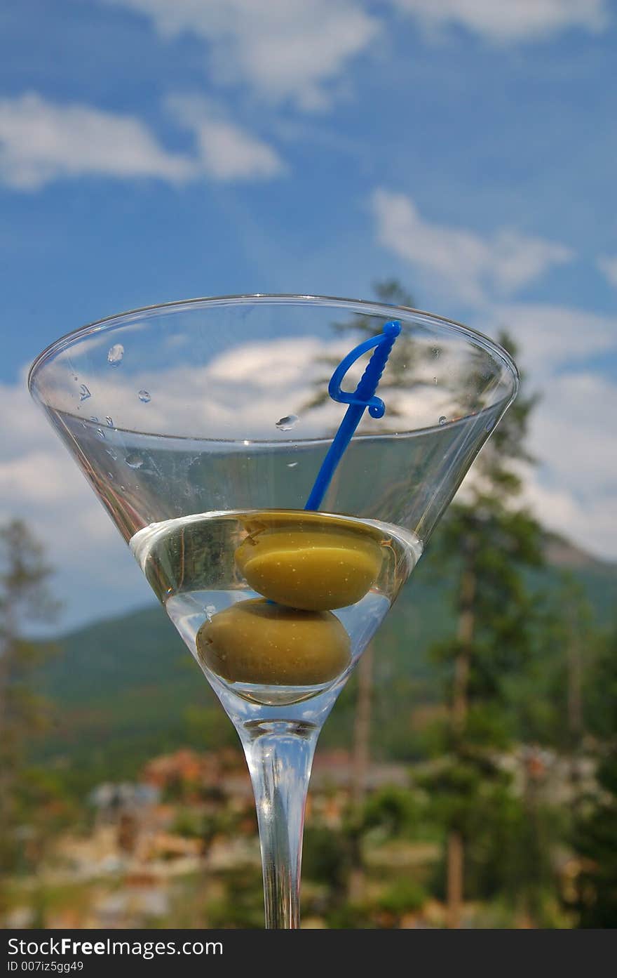 Martini with olives against the backdrop of a partly cloudy blue sky. Martini with olives against the backdrop of a partly cloudy blue sky