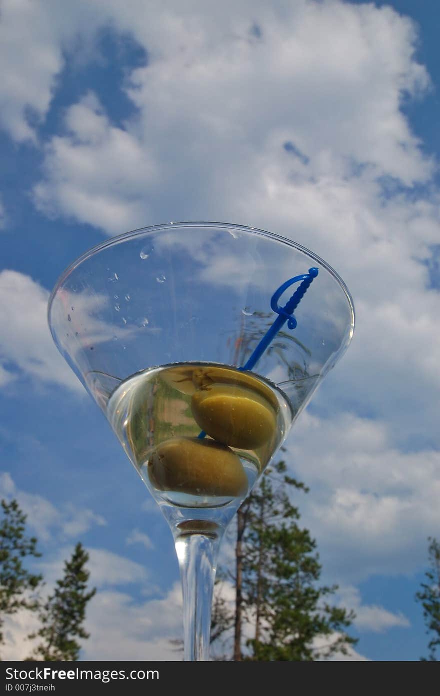 Martini with olives against the backdrop of a partly cloudy blue sky. Martini with olives against the backdrop of a partly cloudy blue sky