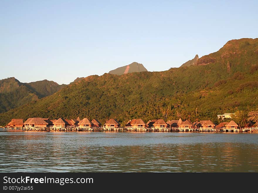 Tropical hotel bungalows at sunrise, on the lagoon