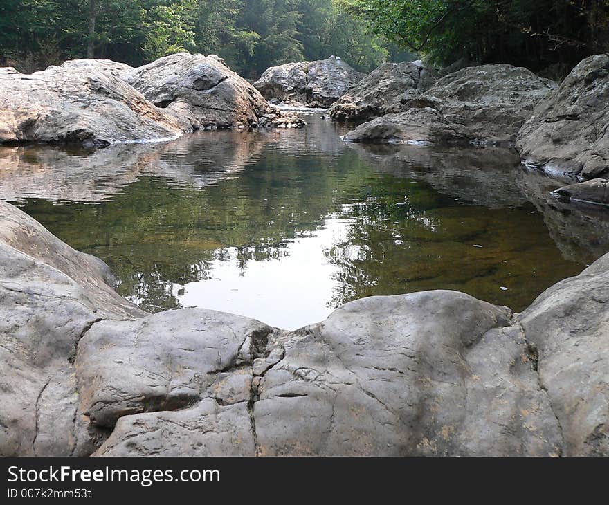 A rocky stream flowing to a small pool of water. A rocky stream flowing to a small pool of water.