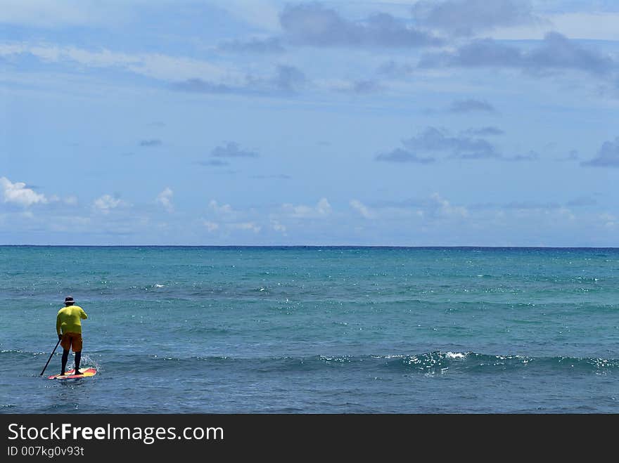 A paddle boarder paddleing out to the ocean all alone