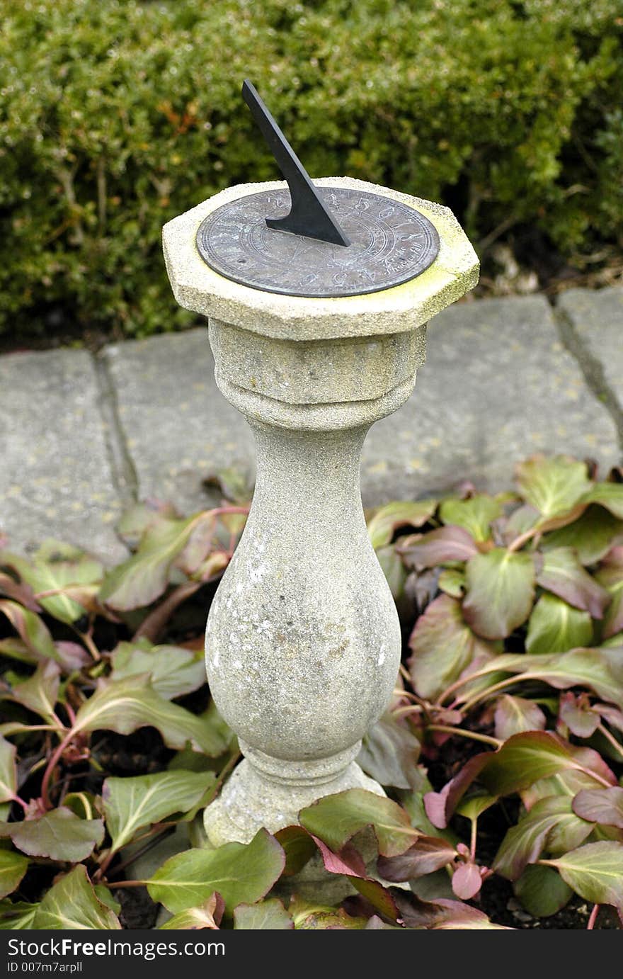 A sundial on a pillar in an English country garden. A sundial on a pillar in an English country garden