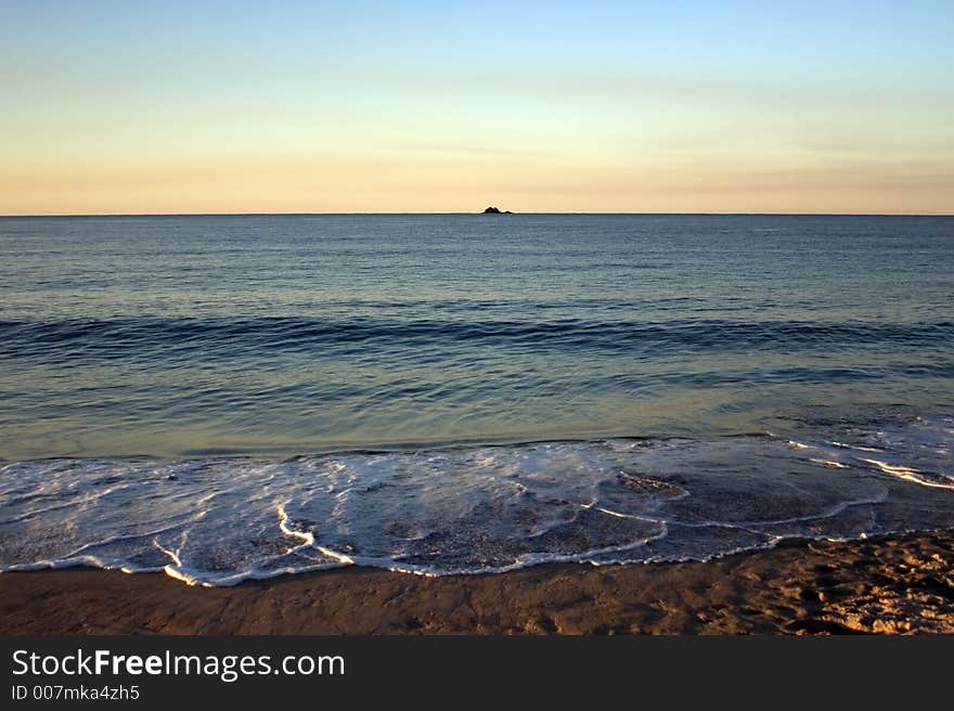 Surf at dusk with distant island. Surf at dusk with distant island