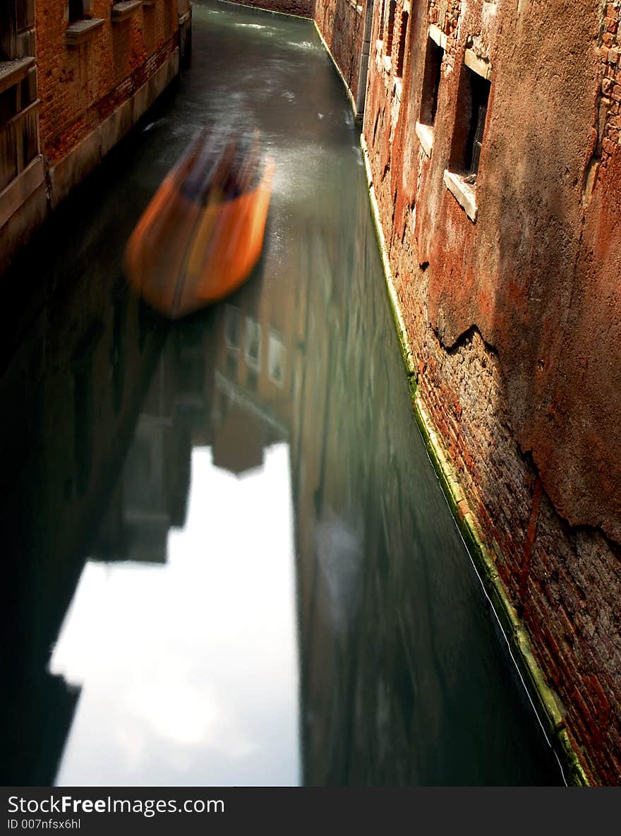 A boat ghosts along the canal in Venice. A boat ghosts along the canal in Venice.