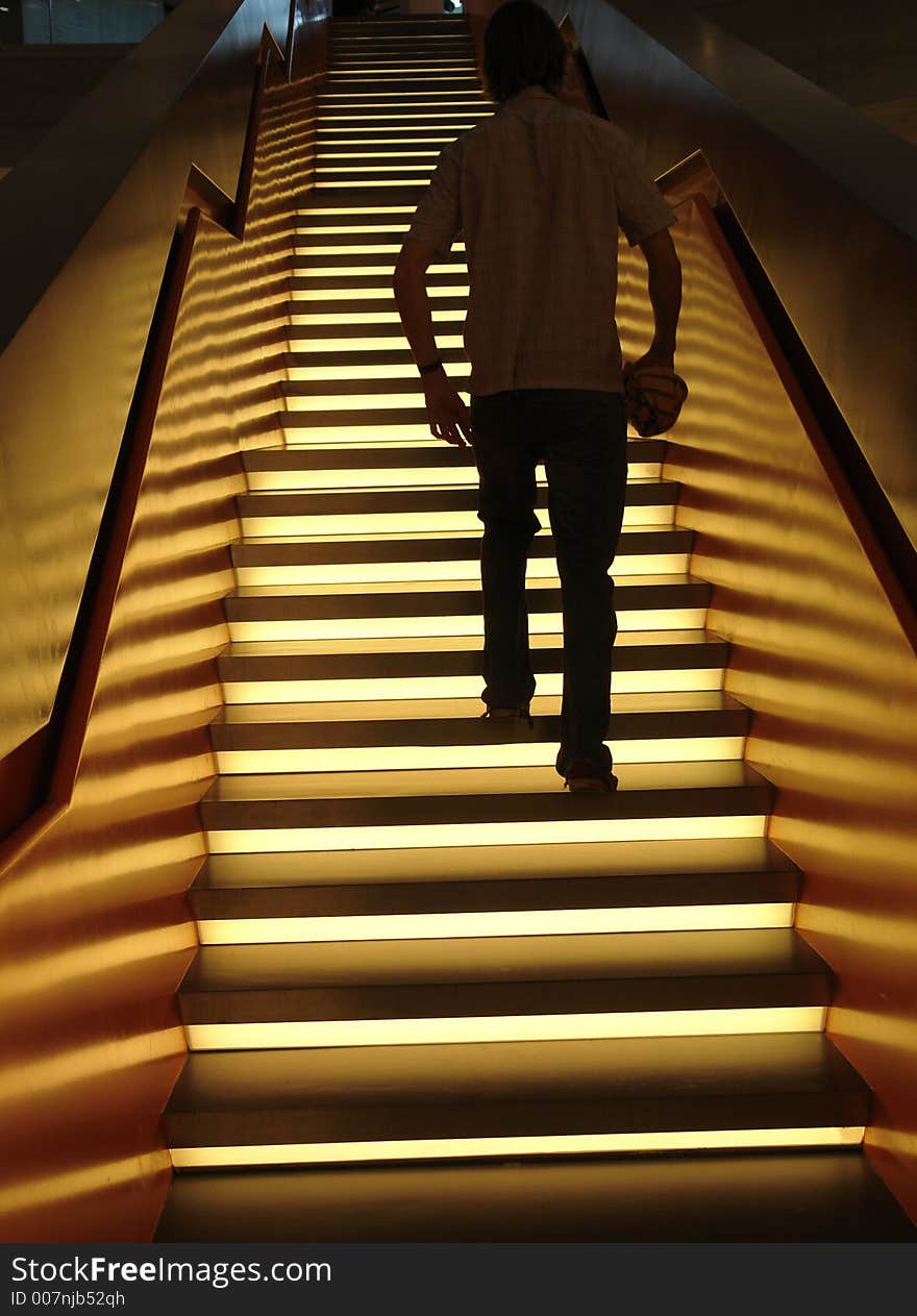 A man walking up an illuminated staircase in a modern building in Germany. A man walking up an illuminated staircase in a modern building in Germany.