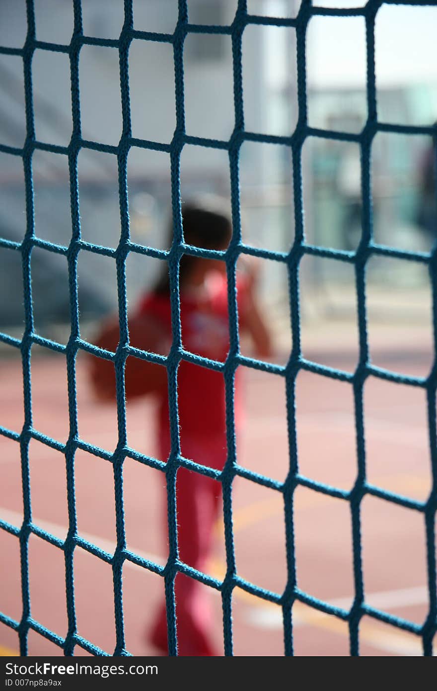 Girl playing ball out of focus behind a net