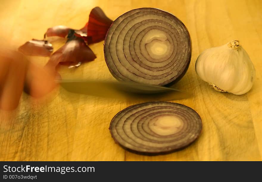 Onion and garlic on chopping board with knife