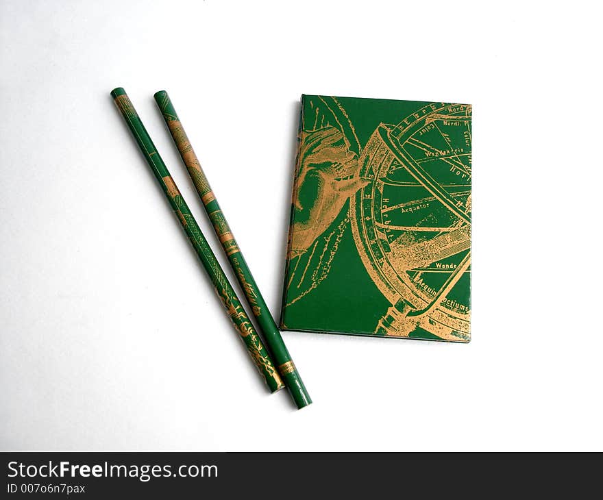 Green notebook with two green pencils on a white background