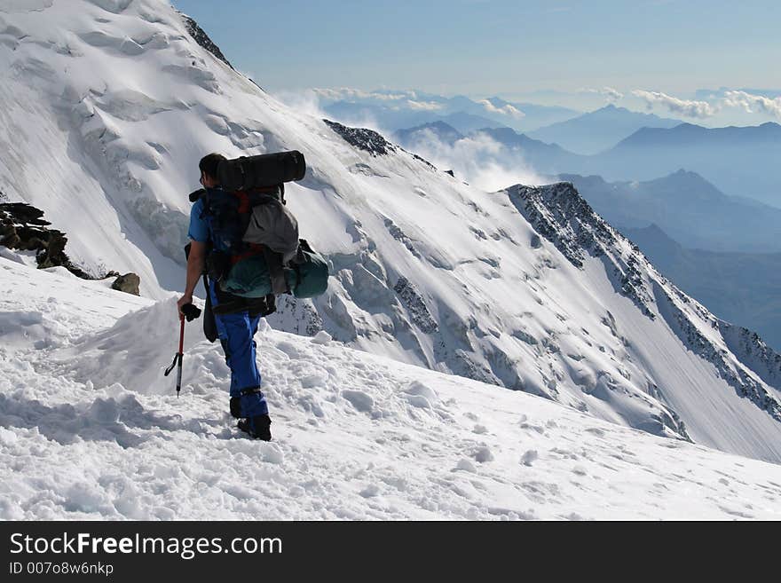 Alpine climbing. Climber with backpack and ice-axe