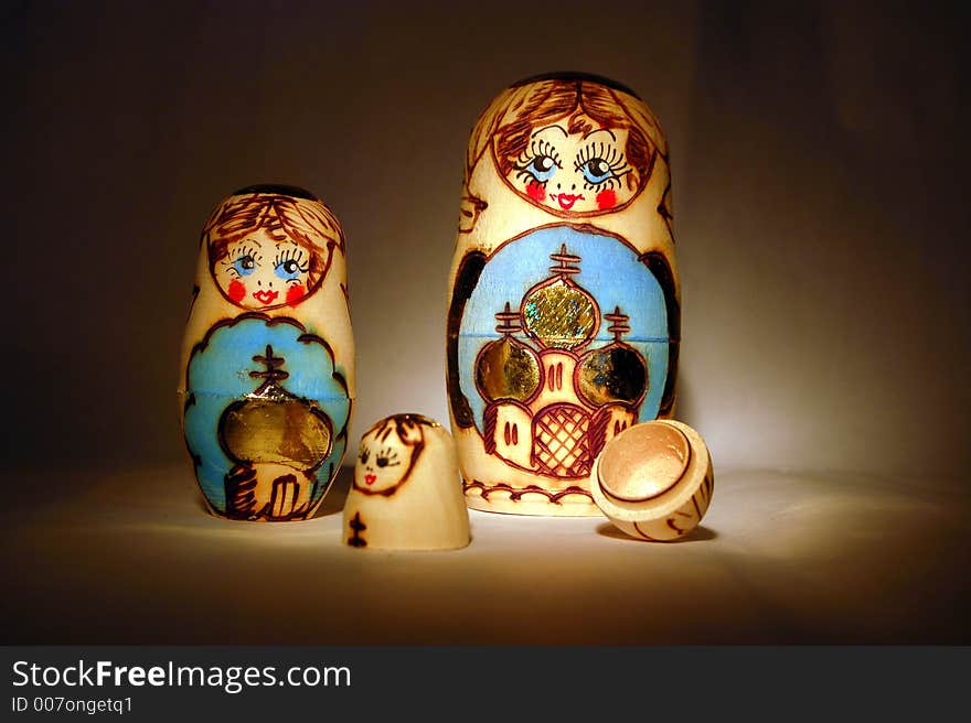 Two babushka dolls and one broken apart pictured together, light from the side. Two babushka dolls and one broken apart pictured together, light from the side.