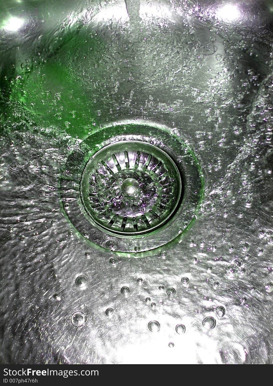 Flowing green water in sink with bubbles