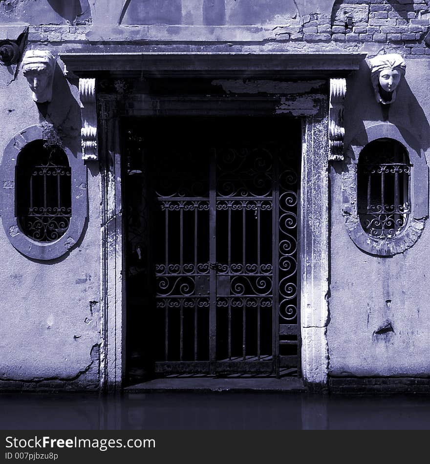 A very spooky looking gate in a building next to a canal in Venice. A very spooky looking gate in a building next to a canal in Venice.