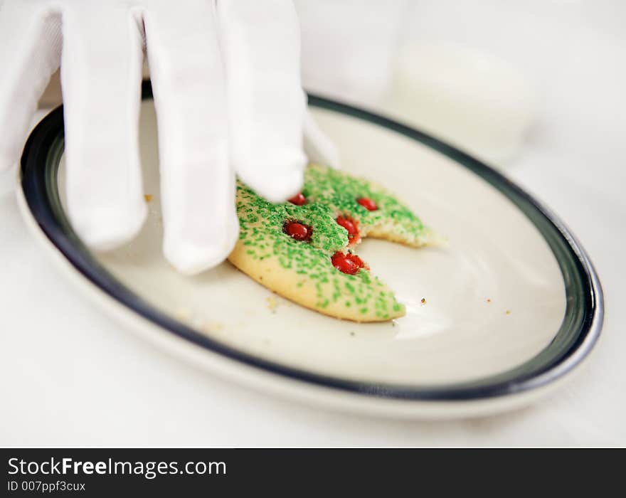 Santa's gloved hands putting down a half eaten Christmas cookie.  Shallow depth of field with focus on cookie. Santa's gloved hands putting down a half eaten Christmas cookie.  Shallow depth of field with focus on cookie.