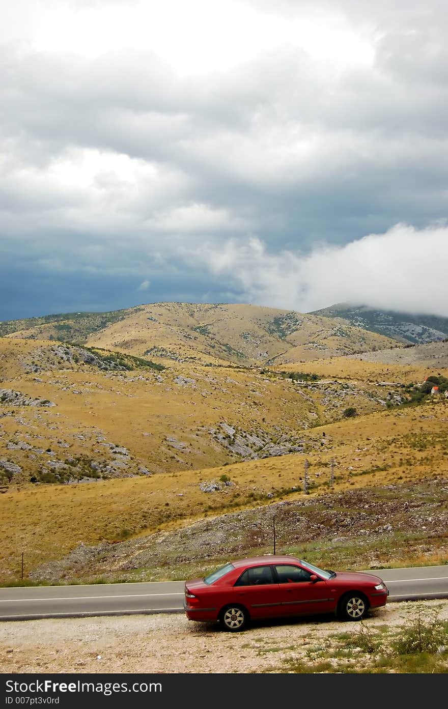 Grey clouds on stormy day in a country and car standing by