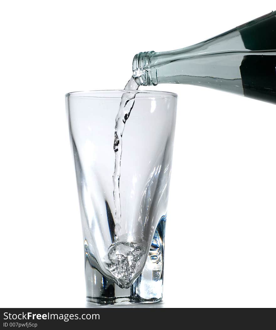 Water being poured from a glass bottle into a glass.  Isolated on white. Water being poured from a glass bottle into a glass.  Isolated on white.