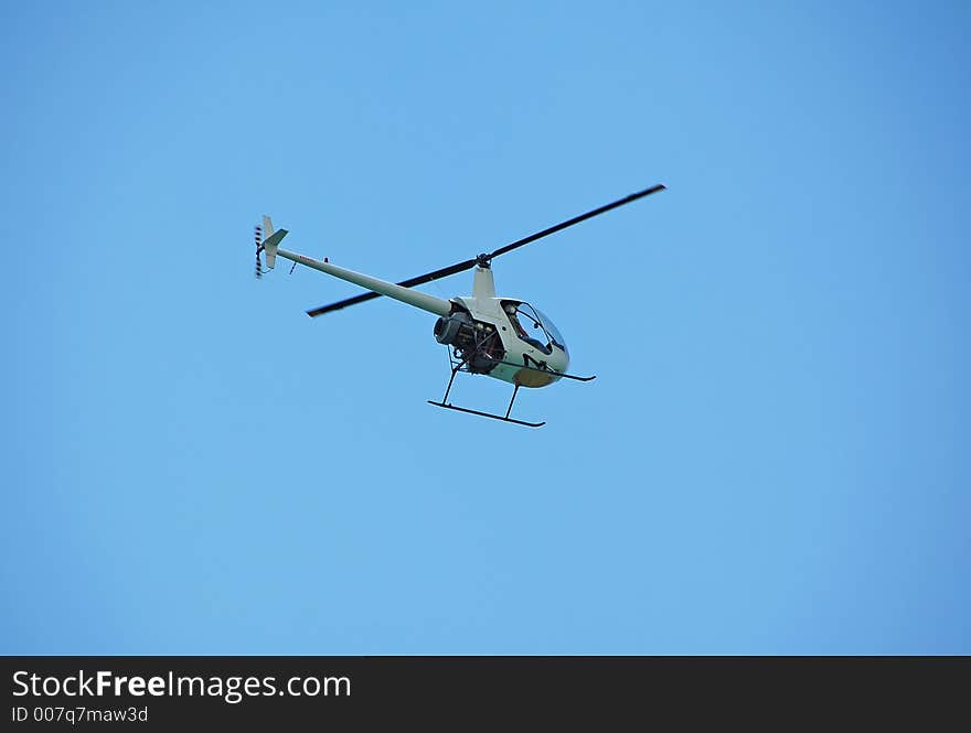 Light Robinson helicopter hovering over beach. Light Robinson helicopter hovering over beach