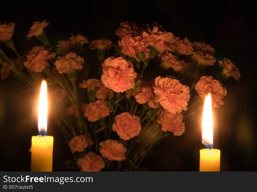 A bunch of carnations partly illuminated by two candles. A bunch of carnations partly illuminated by two candles