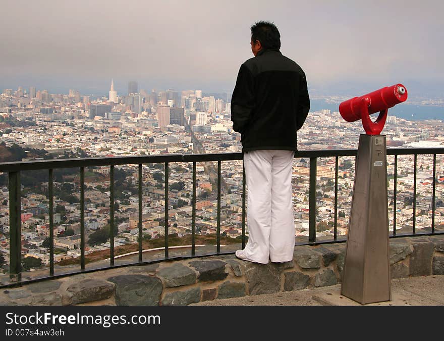 Typical coin-operated monocular on a viewing platform above a city and a man