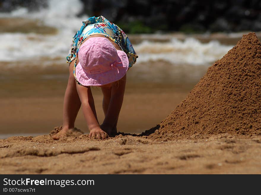 A small girl is building a sand tower. A small girl is building a sand tower