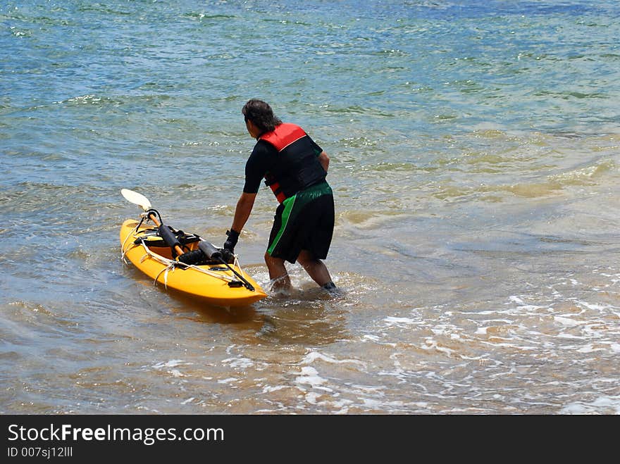 A man with kayaki boat going into the water. A man with kayaki boat going into the water