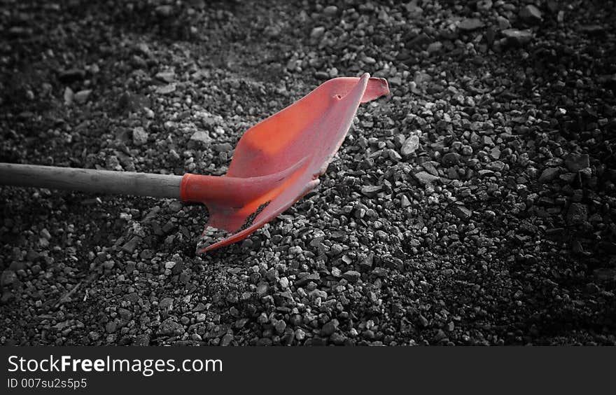 Old, broken red shovel in gravel