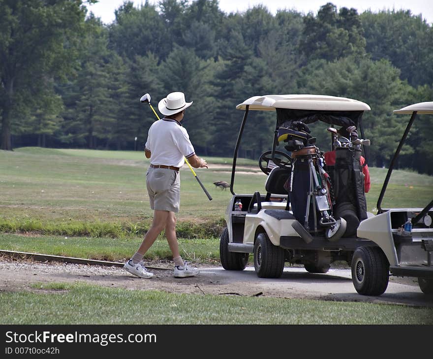 Senior golfer with large brimmed hat on the links.