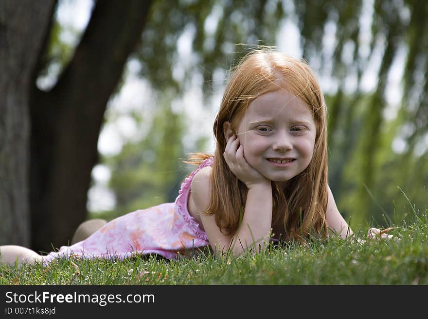 Small redheaded girl laying in grass contemplating the world around her. Small redheaded girl laying in grass contemplating the world around her.