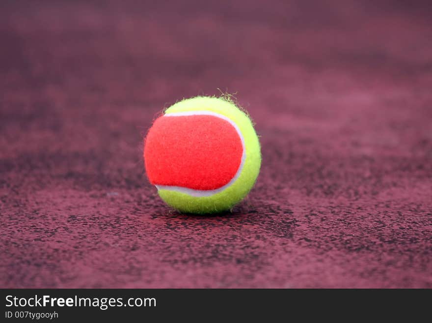 Yellow and orange tennis ball on the ground