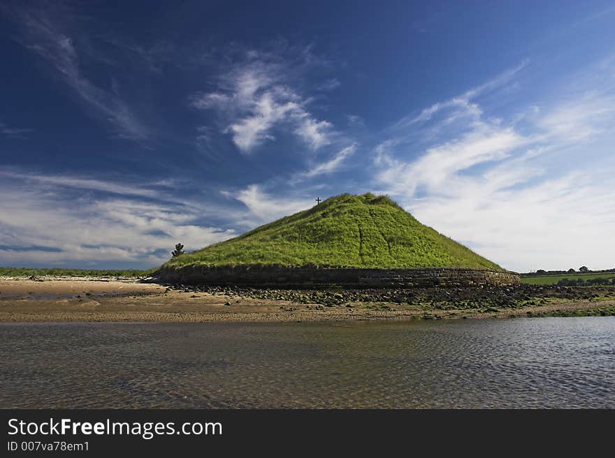 Mound with cross on it behind estuary. Mound with cross on it behind estuary