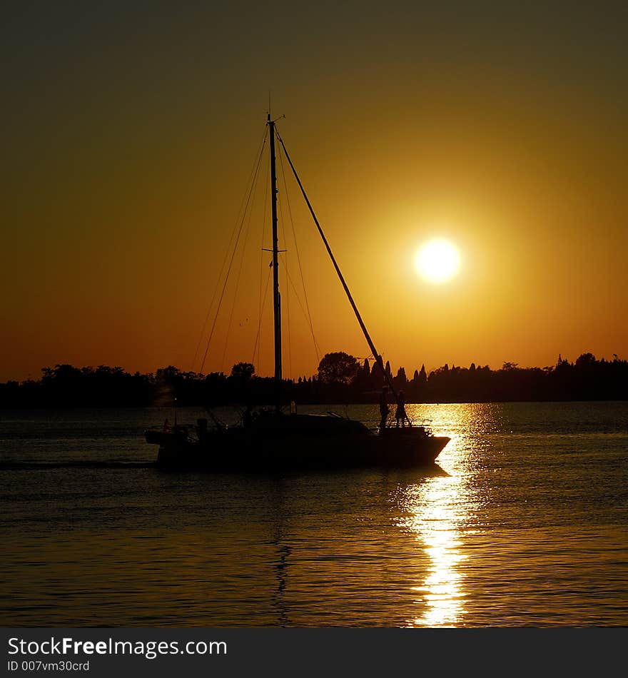 A wonderful sun down in the Venetian lagoon, with a sail boat gliding by. A wonderful sun down in the Venetian lagoon, with a sail boat gliding by.