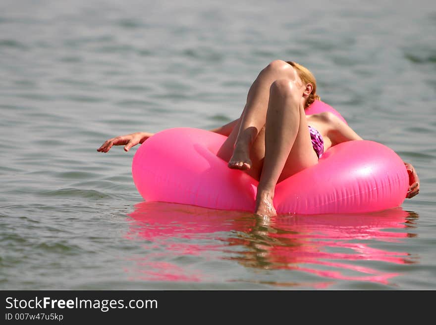 Women taking a sun bath on a pink raft. Women taking a sun bath on a pink raft