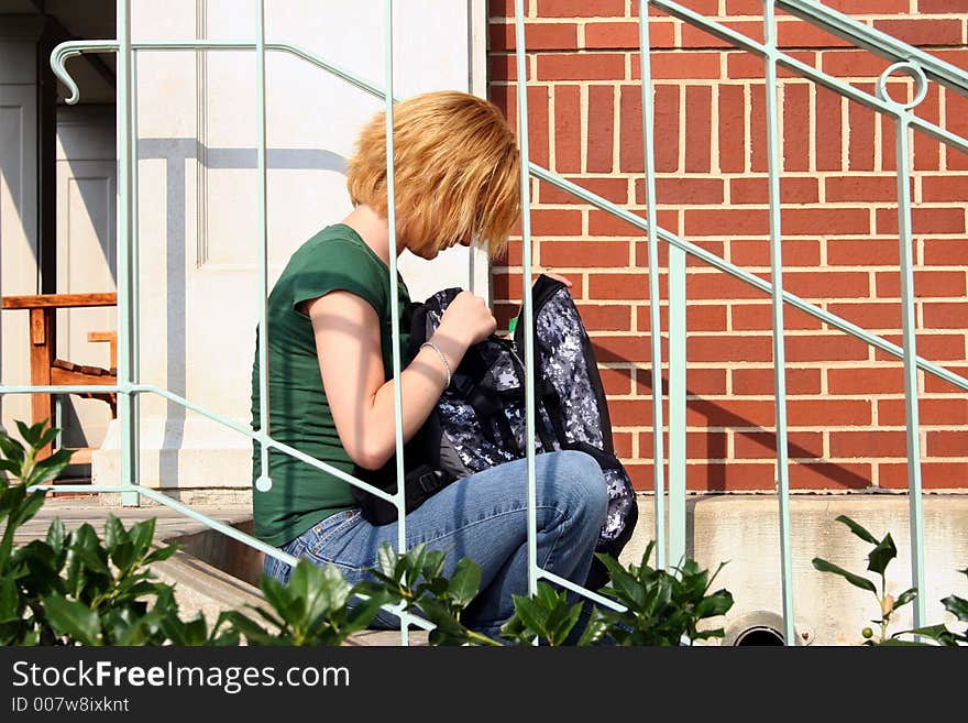 Young girl sitting on steps going through bag. Young girl sitting on steps going through bag