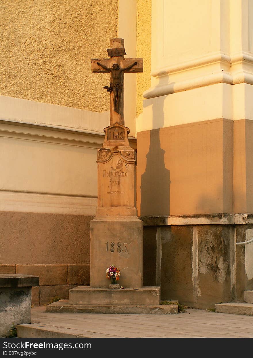 Crucifix near old church with flowers