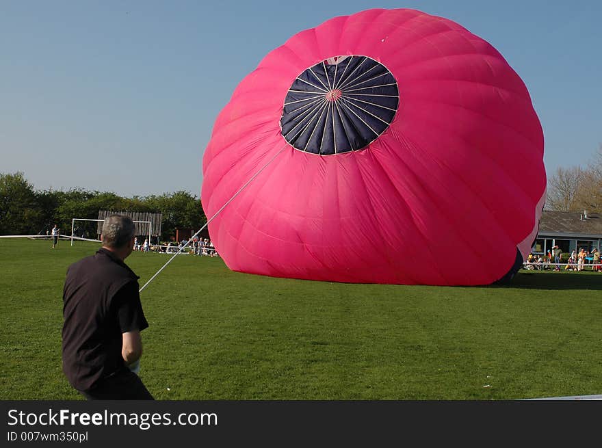 A man ia puling a huge balloon for raising it correctly up.