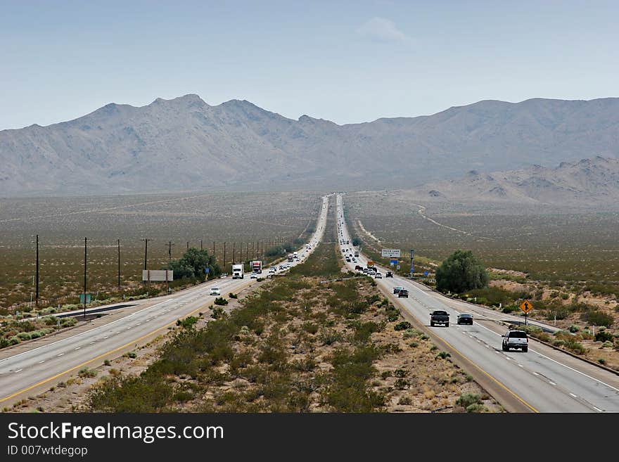 Four lane desert highway stretching to mountains